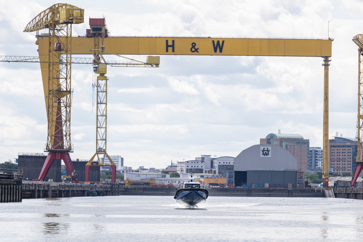 A foiling boat with yellow cranes in the background
