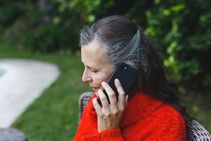 Older Lady Talking On Phone In Garden