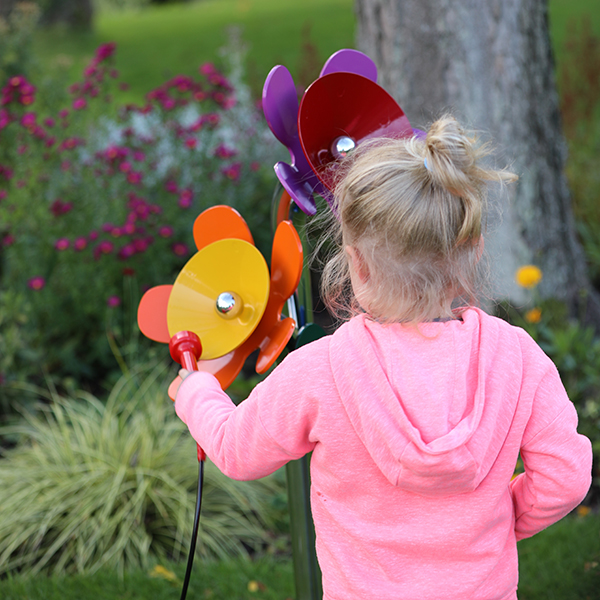 a little girl facing and playing a 'posy' of outdoor musical flowers in a park