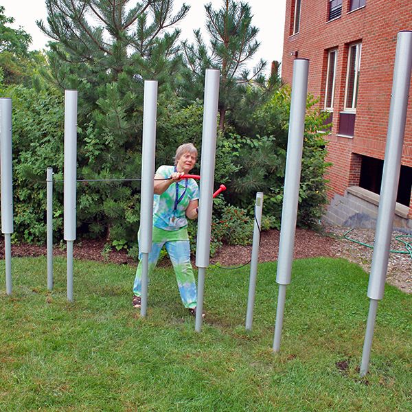 lady playing the tubular bells outdoor musical instruments in the Dino Garden at Liverpool Public Library New York