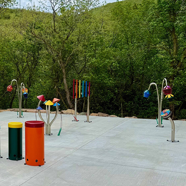 a collection of colorful outdoor musical instruments on a playground surrounded by trees