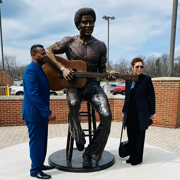 Family members of Bill Withers stand beside a statue of Bill Withers playing guitar at the Bill Withers Memorial Plaza.