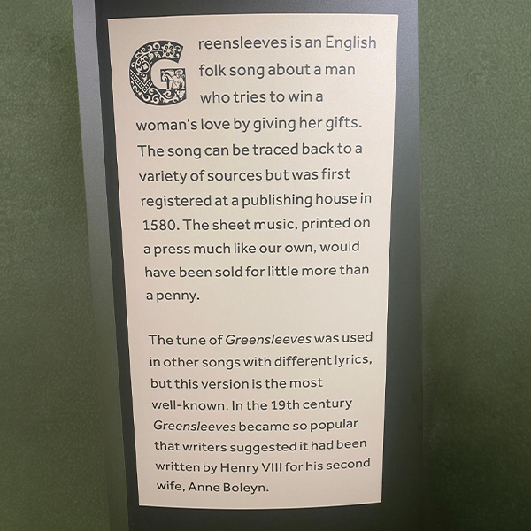 A sign explains the history of the English folk song "Greensleeves," its origins, early publication, and theories about its connection to Henry VIII and Anne Boleyn.