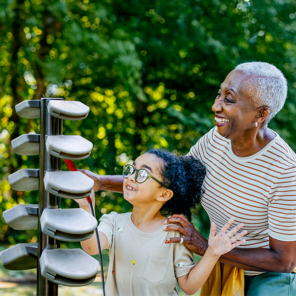 An older woman and a young girl happily playing a musical instrument together, sharing a moment of joy and creativity.