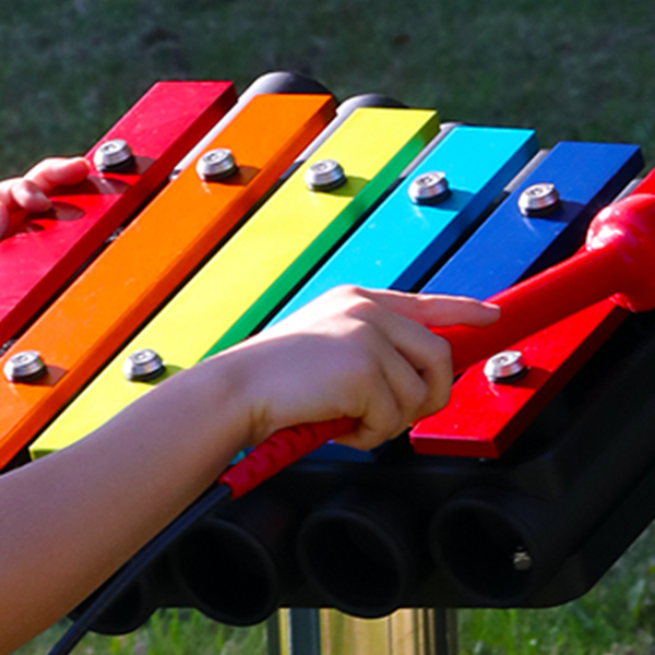 close up image of the rainbow colored notes of a small outdoor xylophone in a garden