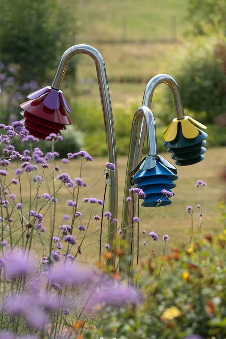a set of three outdoor musical flowers on stainless steel legs in a summer garden