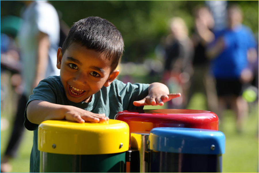 Young child independently exploring music through open‑ended play on an outdoor instrument