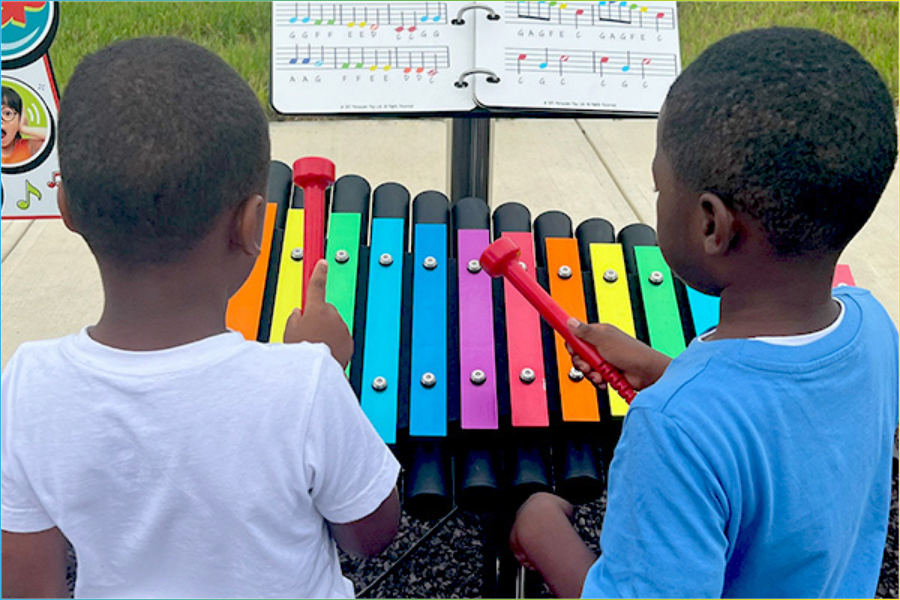 Children exploring sound and movement through music in an open‑ended outdoor play environment