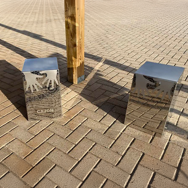 Two outdoor metal cajon drums positioned on a brick path at the Bill Withers Memorial Plaza.