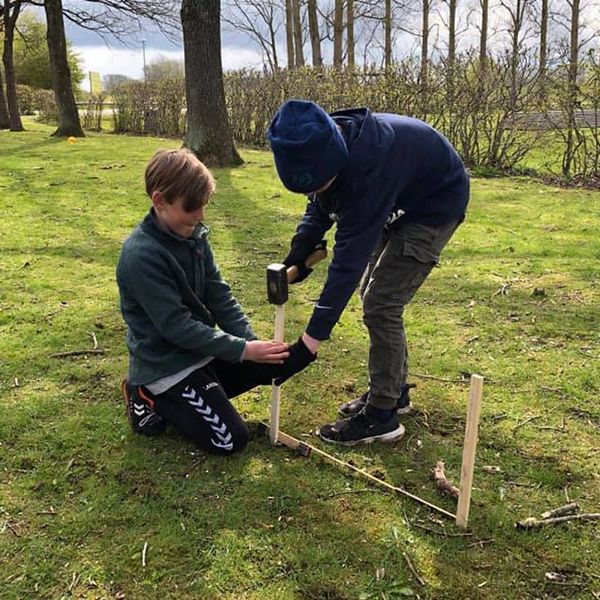 two schoolboys hammering stakes into the ground ready for new outdoor musical instruments