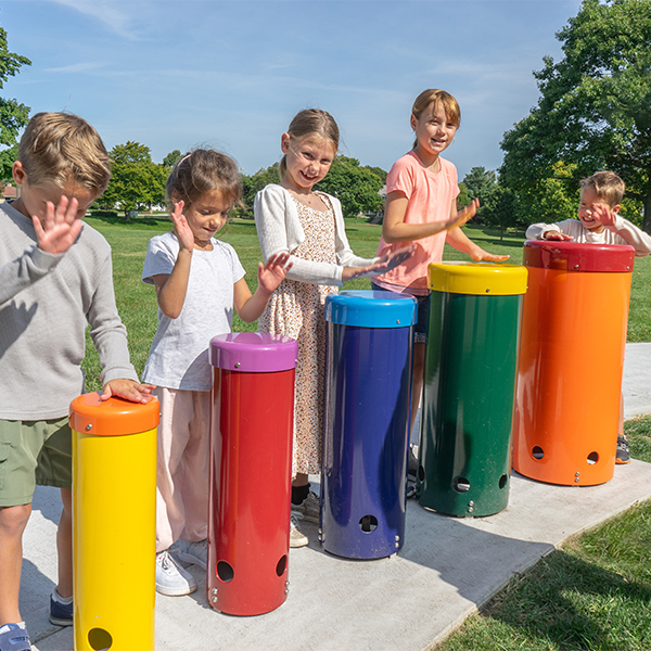 Five children each sttod behind a different colored outdoor drum in a musical playground