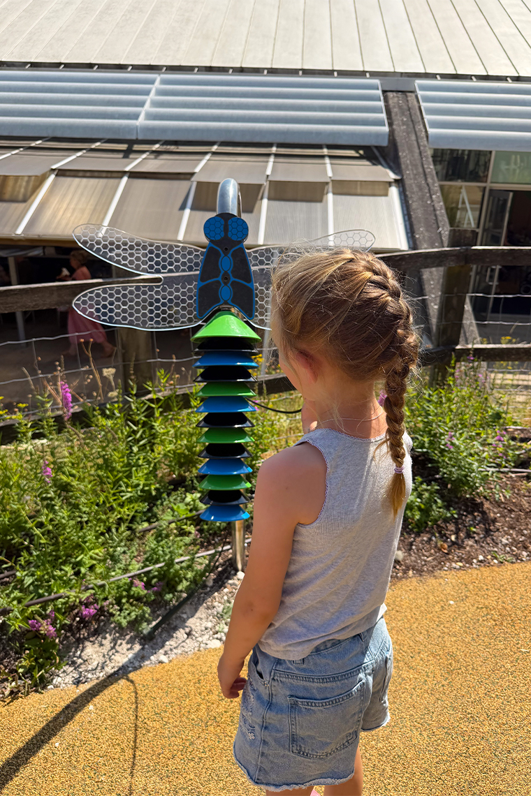 a young girl playing an outdoor musical instrument in a science center music garden