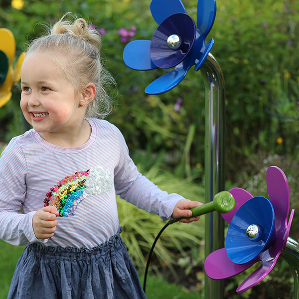 a young girl playing a musical flowers outdoors in a sensory garden or playground