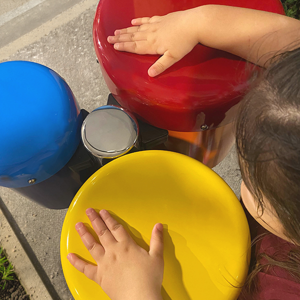 an birds eye image of a child playing colorful outdoor bongo drums in a museum garden