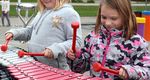two girls playing on a large outdoor xylophone in a school playgrounds